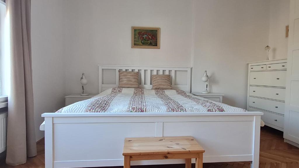 1 cama blanca grande en un dormitorio con taburete de madera en Mona Lisa Apartment, en Bratislava