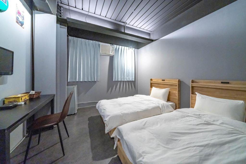 Habitación de hotel con 2 camas, escritorio y ordenador en 新橙居, en Dalin