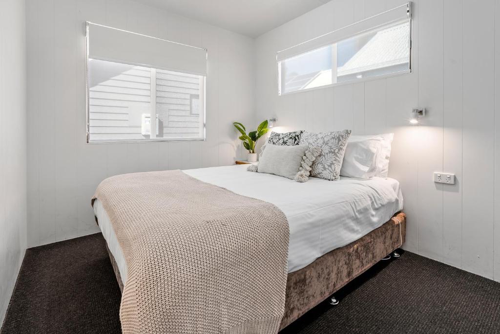 a white bedroom with a large bed with pillows at BIG4 Tasman Holiday Parks - Tathra Beach in Tathra