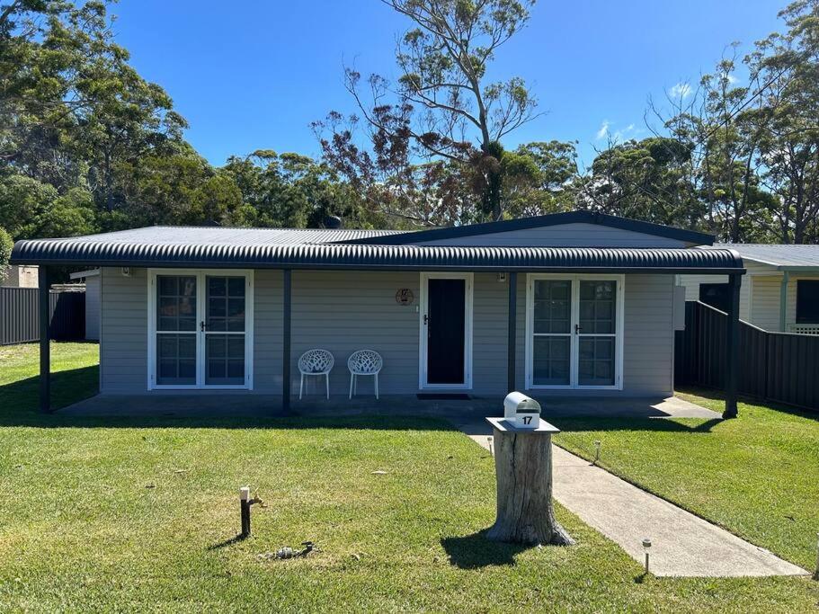 a small house with a tree stump in front of it at Elanora - home by the sea in Sussex Inlet in Sussex inlet