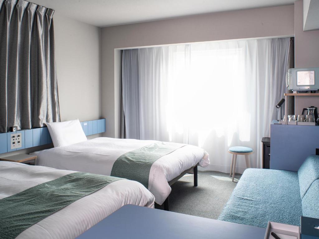 a hotel room with two beds and a window at Vessel Inn Takadanobaba Ekimae in Tokyo