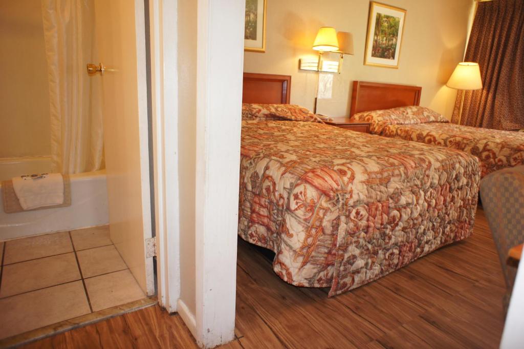 a hotel room with two beds and a bathroom at Executive Inn & Suites in Orange