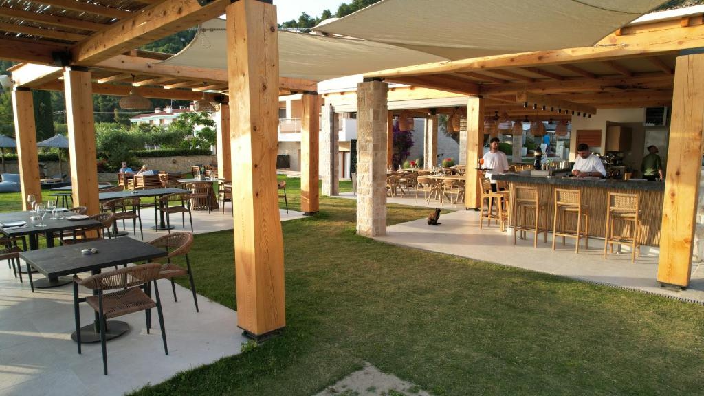 a patio with tables and a bar with people in the background at Olympion Sunset Halkidiki in Fourka