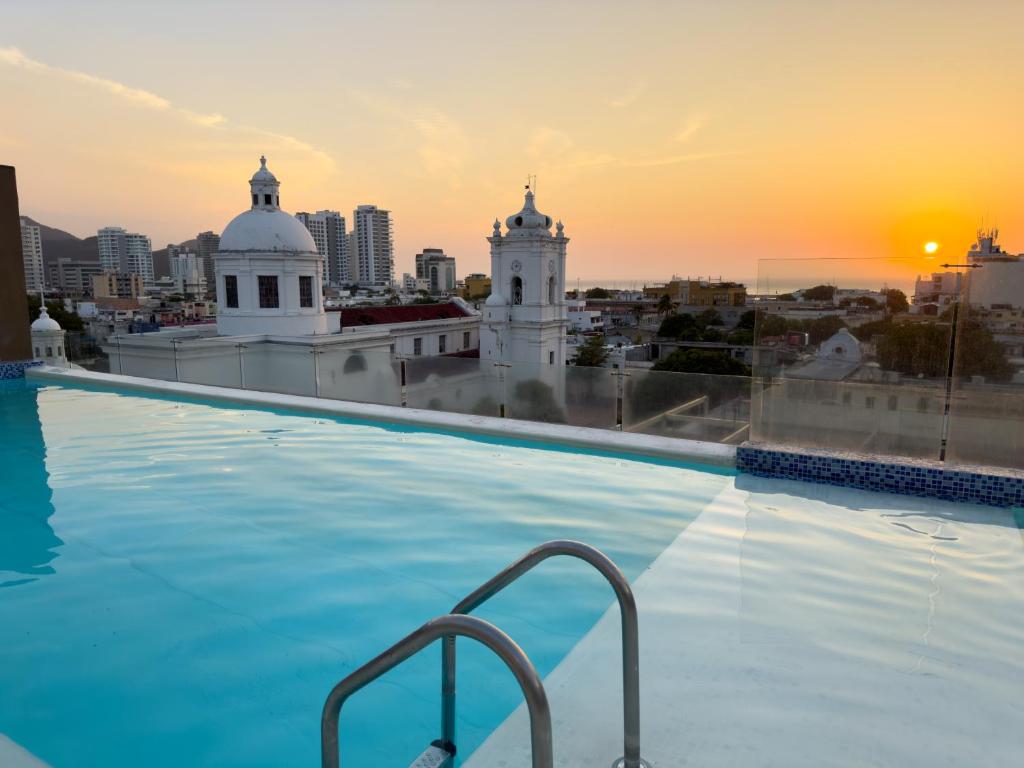 a swimming pool on the roof of a building with the sunset at Hotel Catedral Plaza in Santa Marta