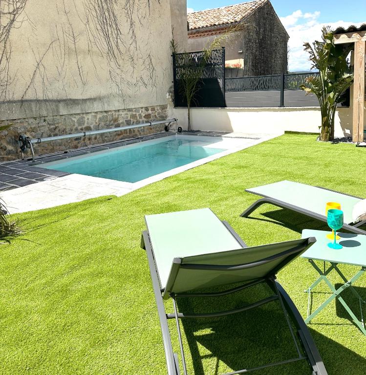 une cour arrière avec une piscine avec une table et une chaise dans l'établissement Le Petit Mas Courriol, à Courry