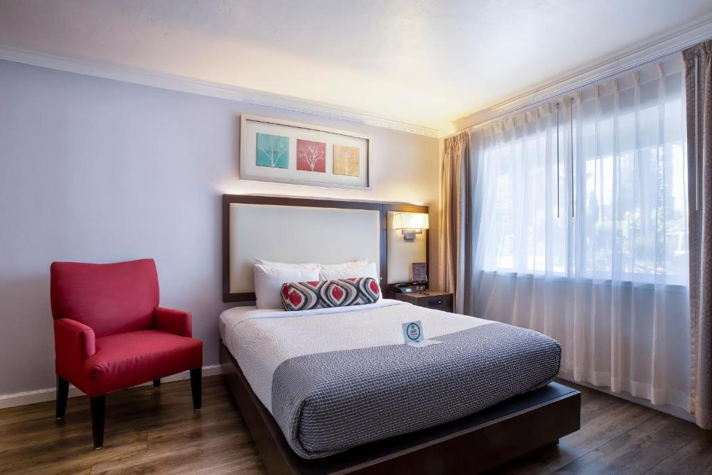 Un dormitorio con una cama y una silla roja. en The Palo Alto Inn, en Palo Alto
