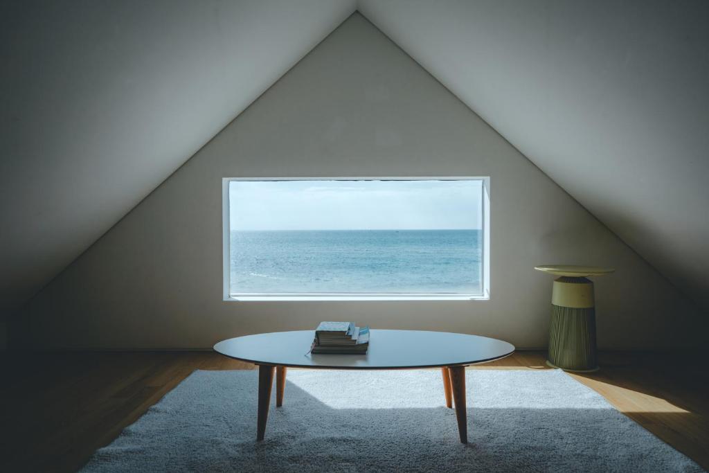 um quarto com uma mesa em frente a uma janela em Dazayo WolryeongBadang House - Ocean View & Pet Frindely em Jeju