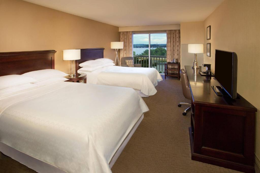 a hotel room with two beds and a flat screen tv at Sheraton Louisville Riverside Hotel in Jeffersonville