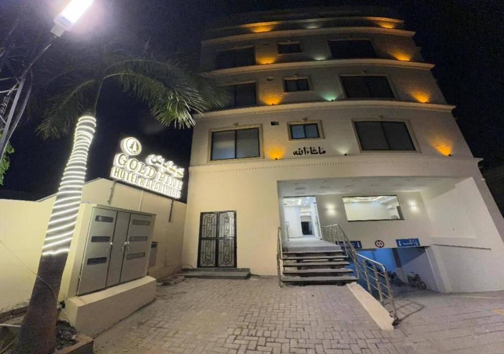 un bâtiment avec un palmier en face dans l'établissement Gold Pine Hotel and Apartments, à Lahore