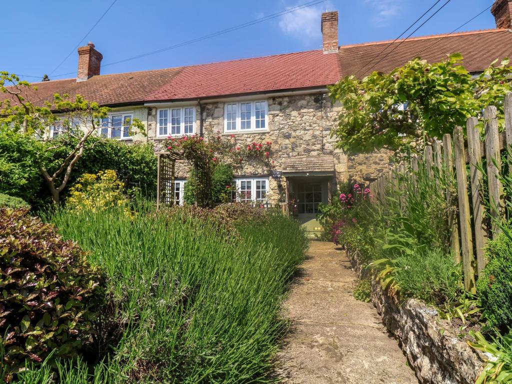 une vieille maison en pierre avec une clôture en bois dans l'établissement Hope Cottage, à Beer