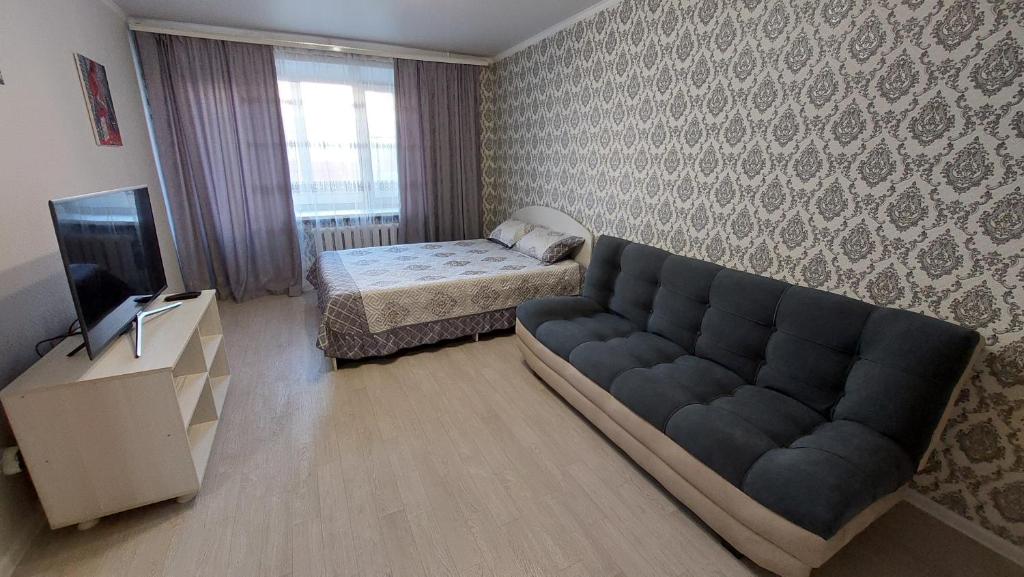 - un salon avec un canapé et un lit dans l'établissement 1 комнатная квартира в Щучинске, à Chtchoutchinsk