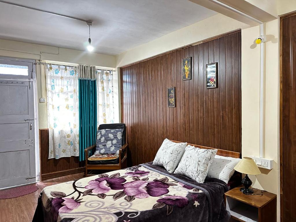 a hotel room with a bed and a chair at Sparid Inn in Darjeeling