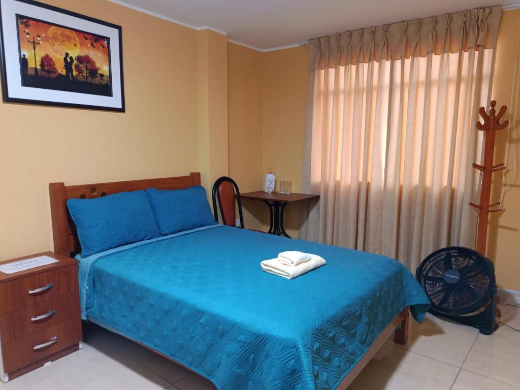Un dormitorio con una cama azul y una mesa en "A y J Familia Hospedaje" - Free tr4nsfer from the Airport to the Hostel en Lima