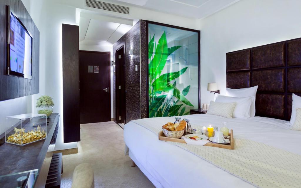 Una habitación de hotel con una cama con una bandeja de comida encima. en Business Hotel, en Túnez