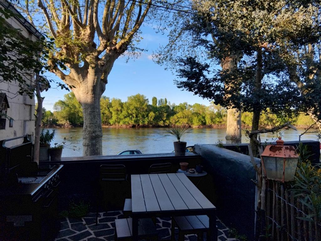 a picnic table with a view of a river at Le Logis des Mariniers in Chalonnes-sur-Loire