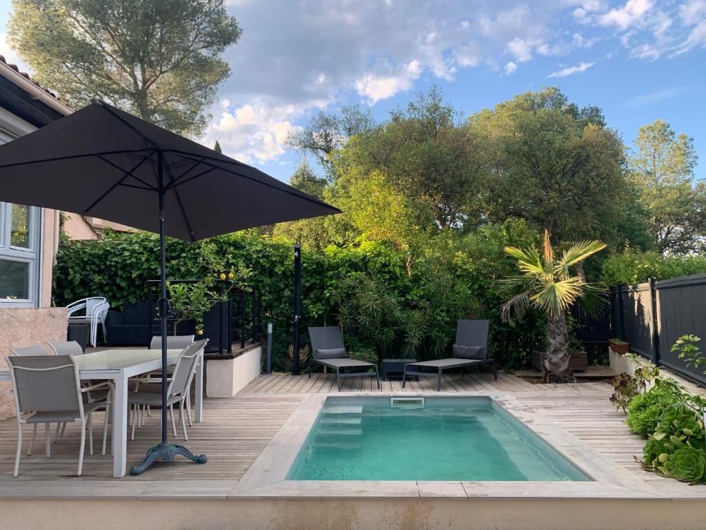une terrasse avec une table, un parasol et une piscine dans l'établissement Frejus Villa, à Fréjus