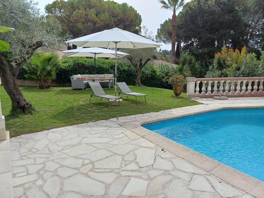un patio avec deux chaises et un parasol à côté d'une piscine dans l'établissement Maison Cannes Mougins, à Mougins
