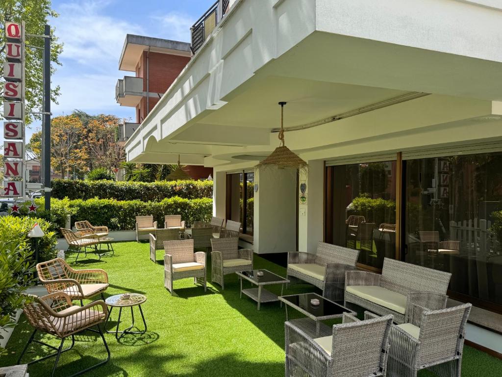 a patio with chairs and tables on the grass at Hotel Quisisana in Riccione
