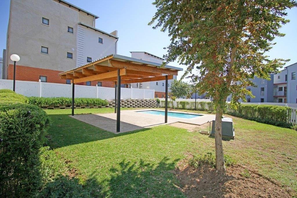 a pavilion in a park next to a building at The Edge of Waterfall in Midrand