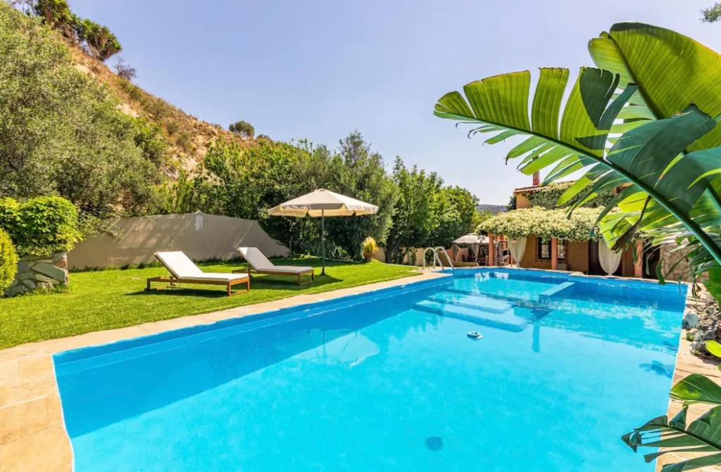 a swimming pool in a yard with two chaise lounges at DM Elegant and Charming Villa in Foinikiá