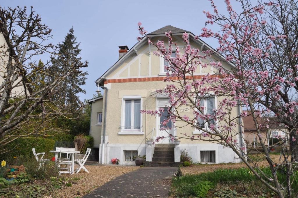 a white house with a table and a tree at La maison de Mado in Saint-Ouen