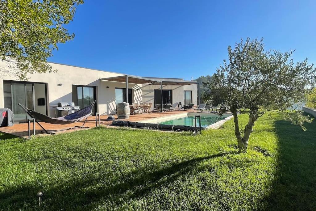 une maison avec une piscine et un hamac dans une cour dans l'établissement Maison contemporaine 180m2 entre Avignon & Nîmes, à Rochefort-du-Gard