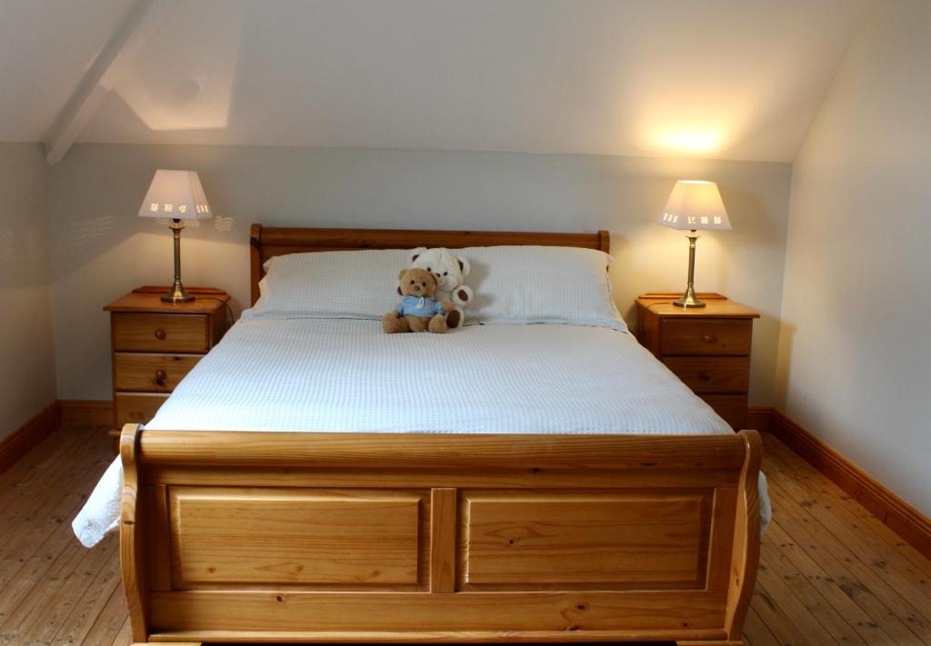 a teddy bear sitting on a bed with two lamps at Mount Leinster View in Bunclody