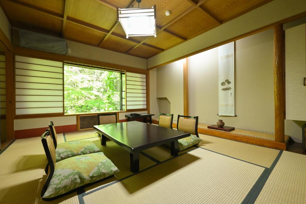 Zimmer mit einem Tisch, Stühlen und einem Fenster in der Unterkunft Osakaya Ryokan in Kusatsu