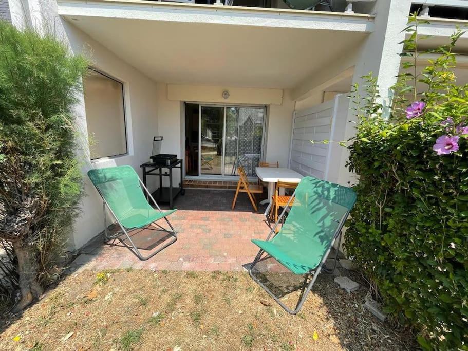 - 2 chaises vertes et une table sur la terrasse dans l'établissement Charmant Cocon avec terrasse à 200m de la plage, à Carnac