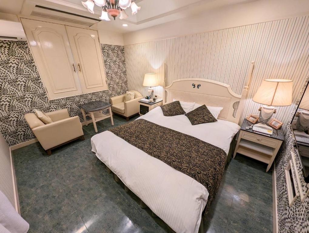 奈良市にあるD-CUBE奈良店の大きなベッドと椅子が備わるホテルルームです。