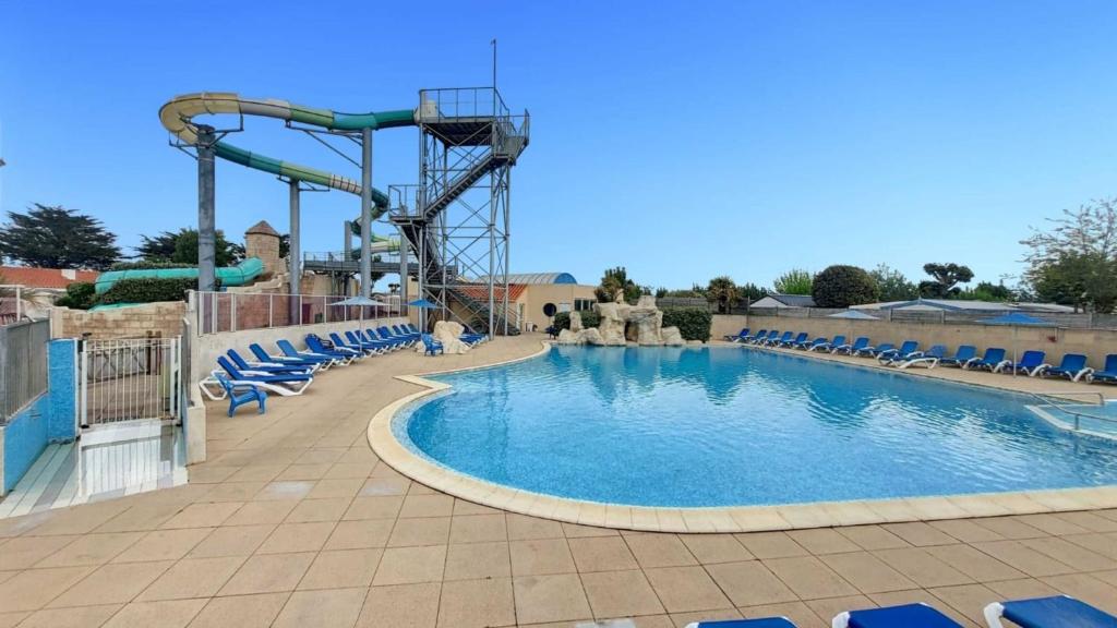 une grande piscine avec des chaises et des montagnes russes dans l'établissement Ti Colibri Sables-dOlonne Nord Camping La Plage, à Saint-Hilaire-de-Riez