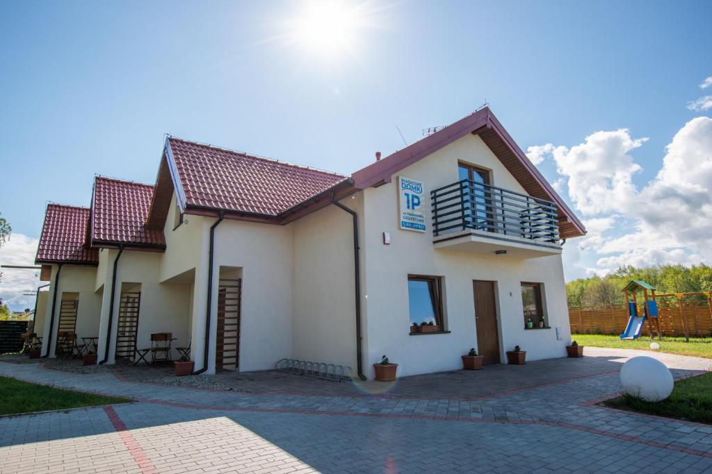 a white house with a red roof at Piaskowe Domki in Grzybowo