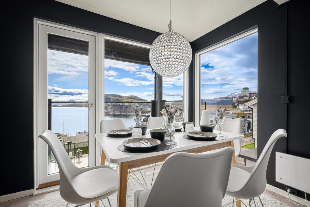 a dining room with a white table and chairs and large windows at AA Home Solgryveien Harstad in Harstad