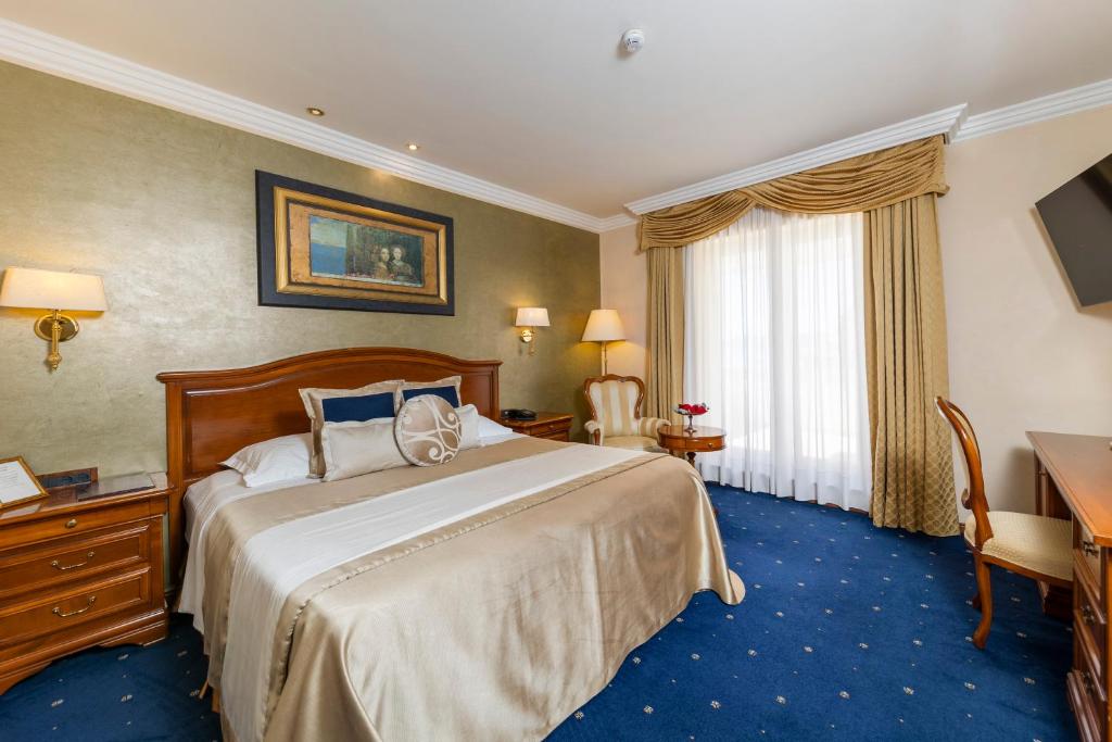 Habitación de hotel con cama, escritorio y TV. en Hotel Niko en Zadar