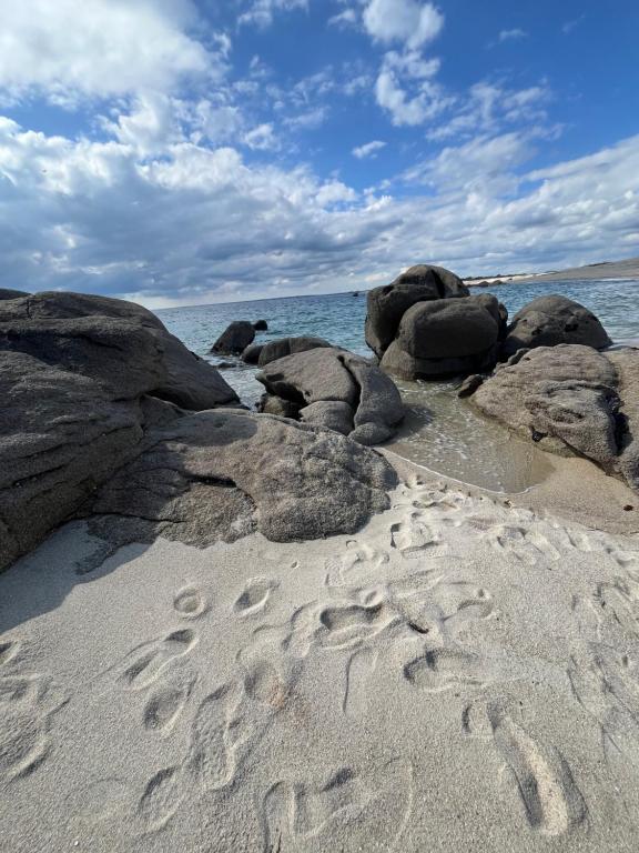 uma praia com pedras e pegadas na areia em MH VAL&YVAN plage, piscine pointe de Trévignon et concarneau em Trégunc