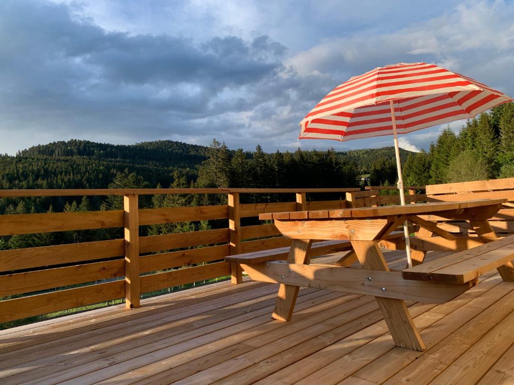 a picnic table with an umbrella on a deck at Le Perchoir, Gîte 7 personnes, Le Grand Valtin in Ban-sur-Meurthe-Clefcy