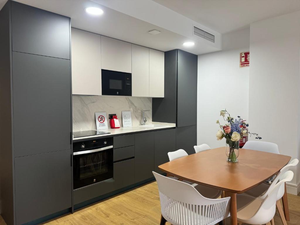a kitchen with a wooden table and white cabinets at Apartamentos Arcos de Montemar in Torremolinos