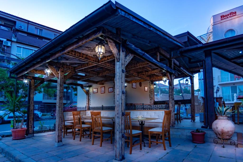 a wooden pergola with tables and chairs on a patio at Family Hotel Berlin Beach Sveti Vlas in Sveti Vlas