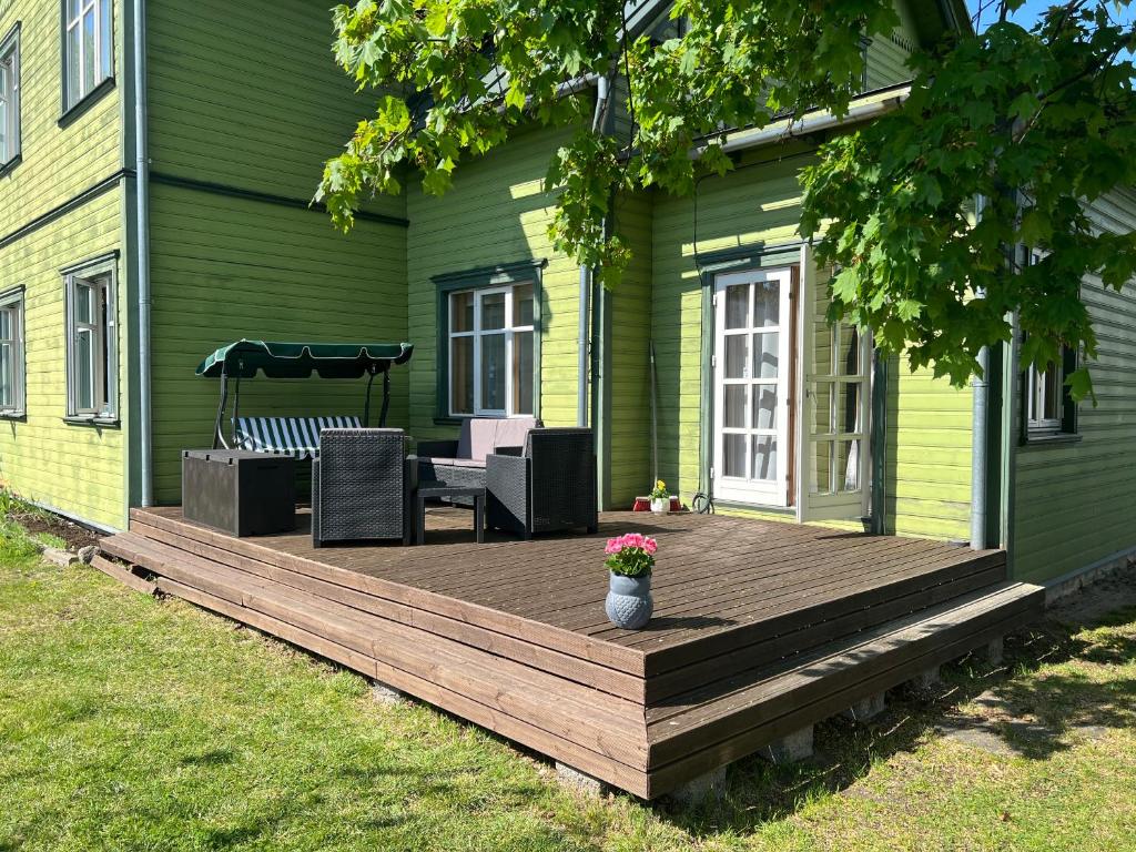 a wooden deck on the side of a green house at Papli Apartment near the Beach in Pärnu