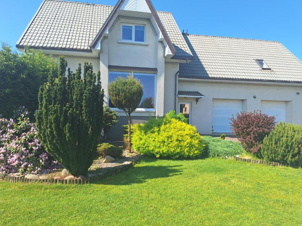 a house with bushes and trees in a yard at Nakvynės namai šalia Klaipėdos in Klaipėda