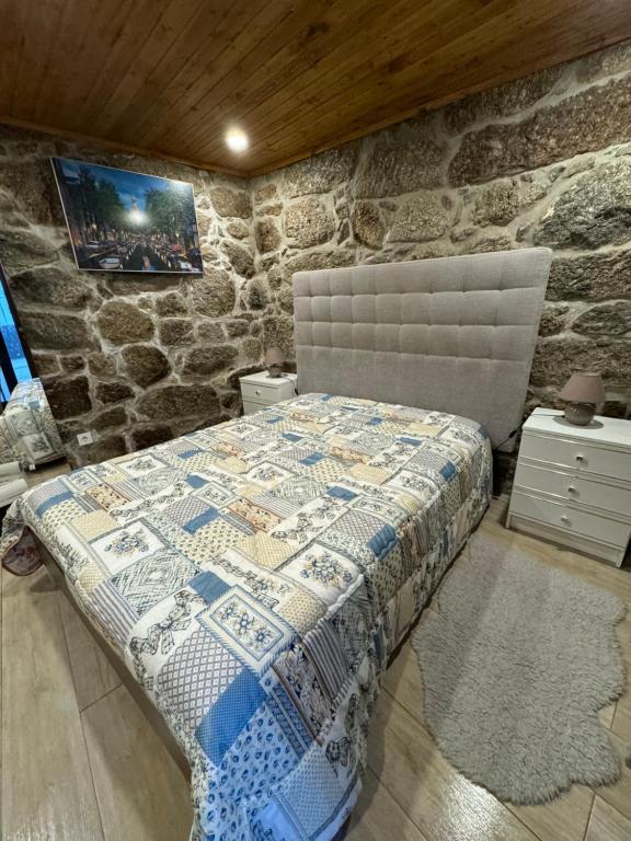 een slaapkamer met een bed in een stenen muur bij Casa d'Alicinha - Férias no Douro in Baião