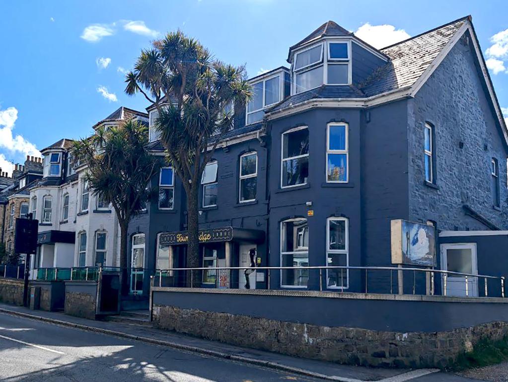 a black building with palm trees in front of it at Town Lodge in Newquay