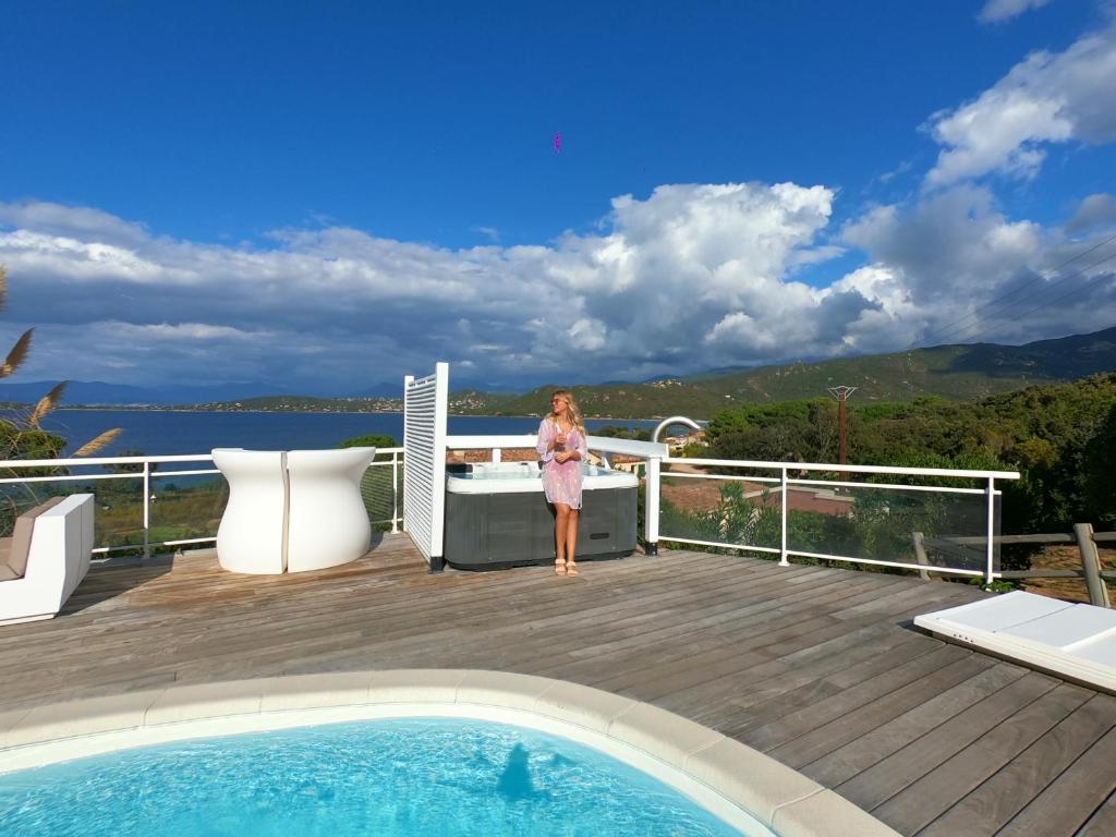 a woman standing on a deck next to a swimming pool at Résidence Aigue Marine in Coti-Chiavari