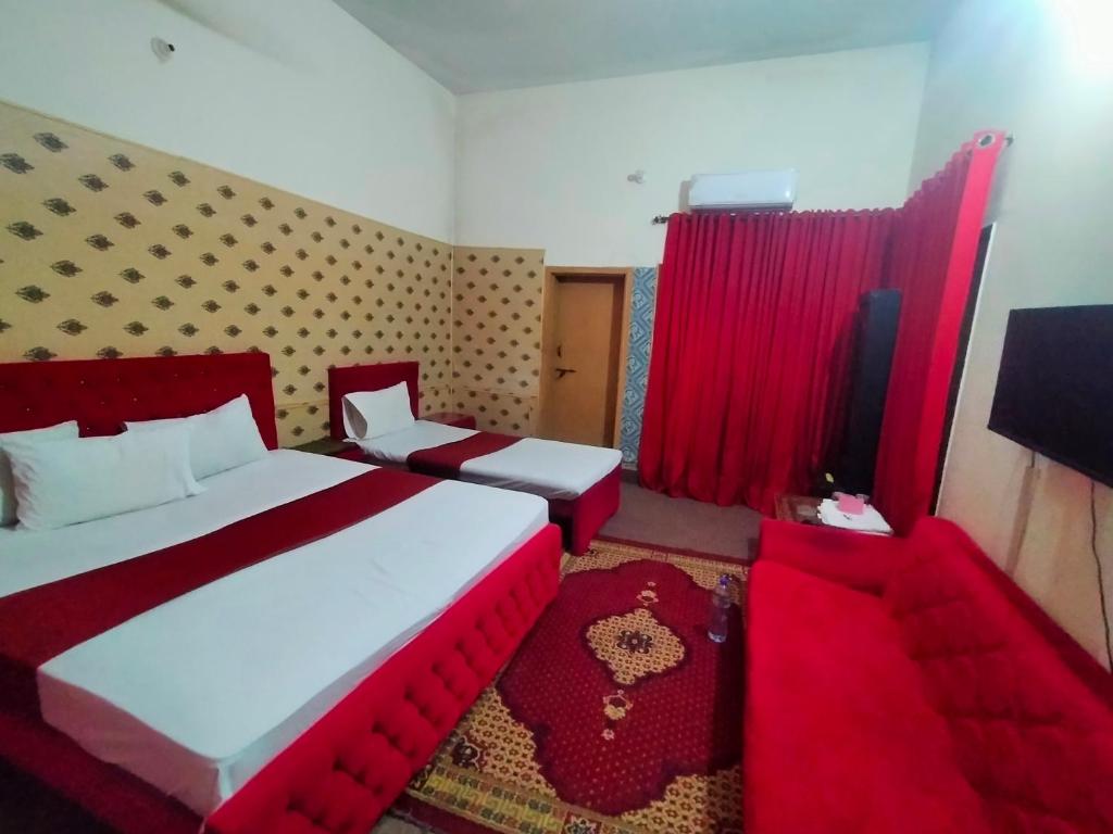 a hotel room with two beds and a chair at Peridot Cottage in Islamabad