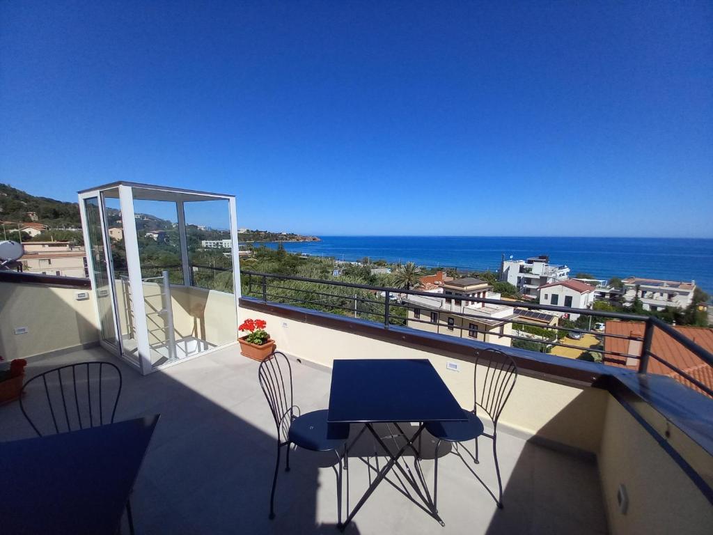 a balcony with a blue table and chairs and the ocean at Holidays Cefalù in Cefalù