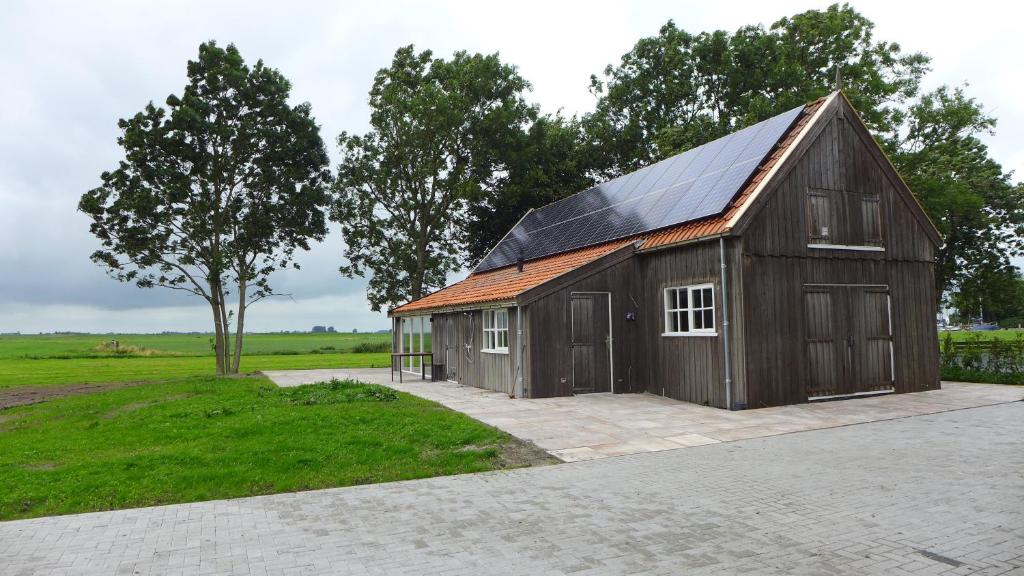a large brown barn with a solar roof at Druvebeam in Oudega