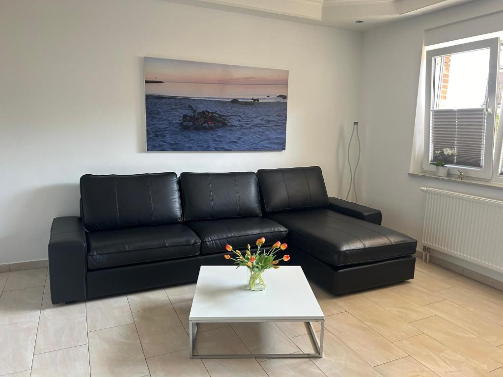 um sofá de couro preto numa sala de estar com uma mesa em Haus Meeresbrise em Grömitz