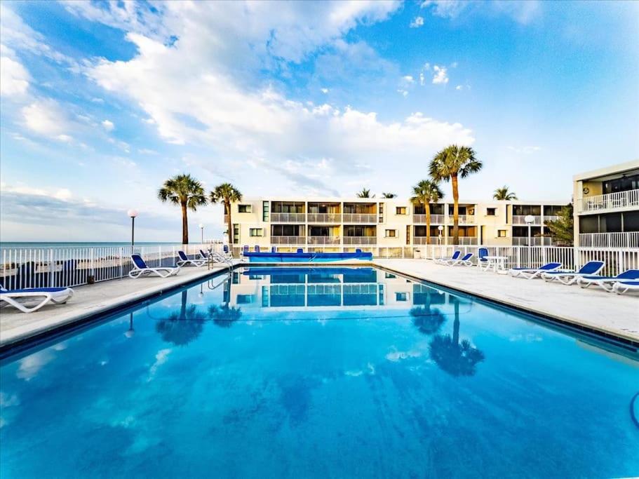 a large swimming pool with chairs and the ocean at Beachfront oasis, heated pool and garden view #17 in Marathon