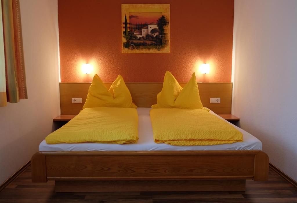 un letto con lenzuola e cuscini gialli in una stanza di Gasthof in der Exlau a Neuhaus