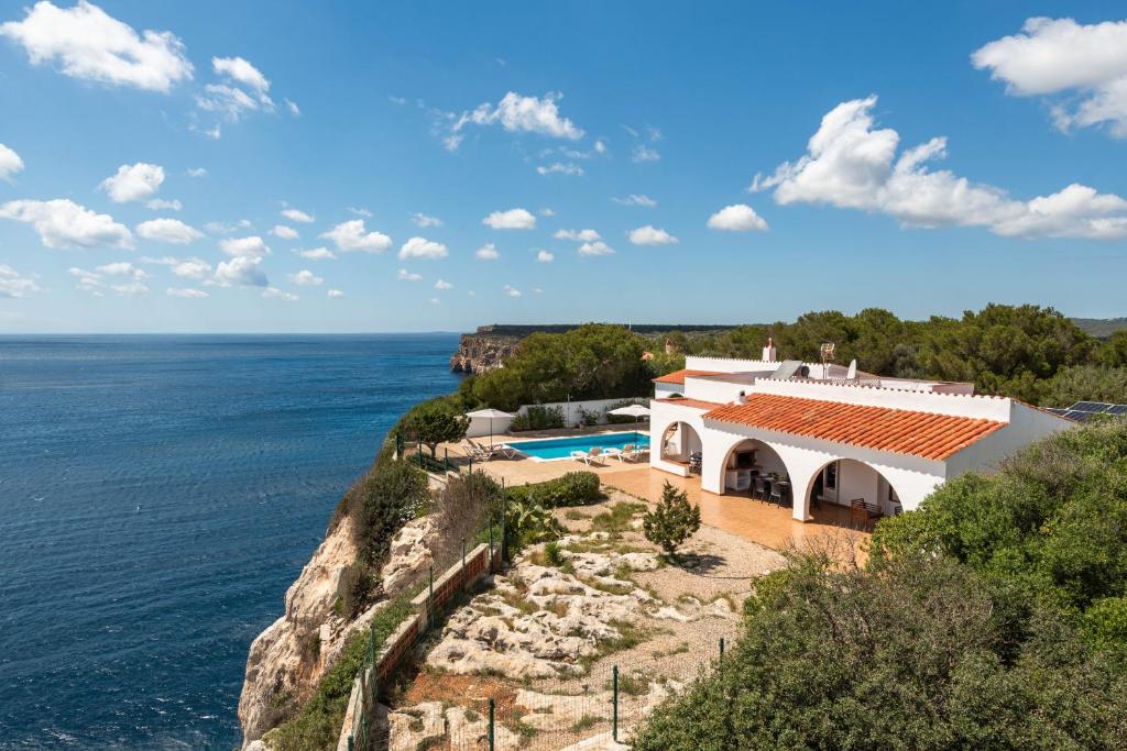 a house on a cliff next to the ocean at Villa Panorama in Cala'n Porter